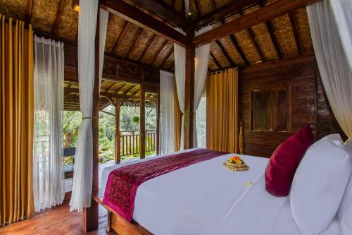 a bedroom with a white bed with red pillows at Tirta Jenar Villas by GenuineHost in Tegalalang