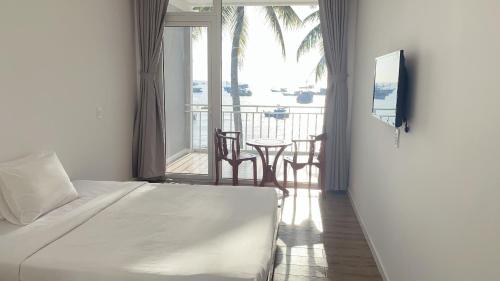 a bedroom with a bed and a balcony with a table at TS Beach House in Phu Quoc