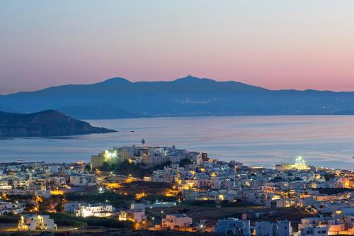 Arco Naxos Luxury Apartments في ناكسوس تشورا: مدينة في الليل مع جبال في الخلفية
