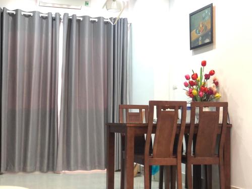 een eettafel met 2 stoelen en een vaas met bloemen bij Căn hộ nghỉ dưỡng Mường Thanh apartment in Da Nang