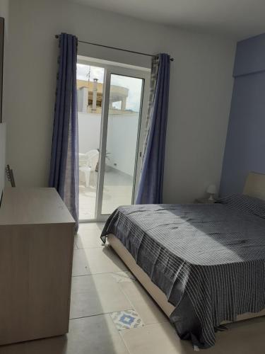 Schlafzimmer mit einem Bett und einer Glasschiebetür in der Unterkunft Mansarda con terrazza a 50 metri dal mare in Balestrate