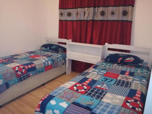 um quarto com 2 camas e uma cortina vermelha em Gansbaai Self-Catering Apartment em Gansbaai