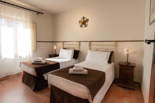a bedroom with two beds and a window at Borgo San Lorenzo a Linari in San Rocco a Pilli