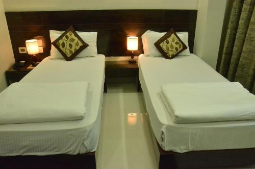 two beds in a hotel room with two lamps at Hotel Sopan Heights in New Delhi