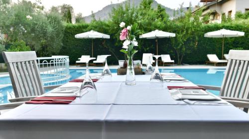 a table with a white table cloth and chairs and a pool at Renka Hotel & Spa in Göcek