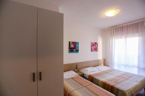 una camera con due letti, un armadio e una finestra di Residence Holiday a Porto Santa Margherita di Caorle