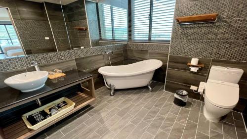 a bathroom with a tub and a toilet and a sink at Kuei Ti Wan Hotel in Checheng