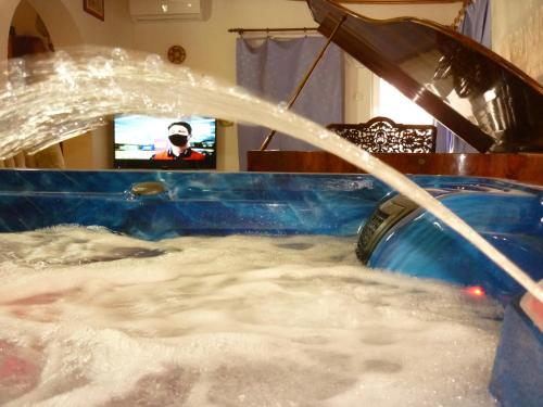 a bath tub filled with water with a person in the background at R1 Rolléder Apartman-ház in Siklós