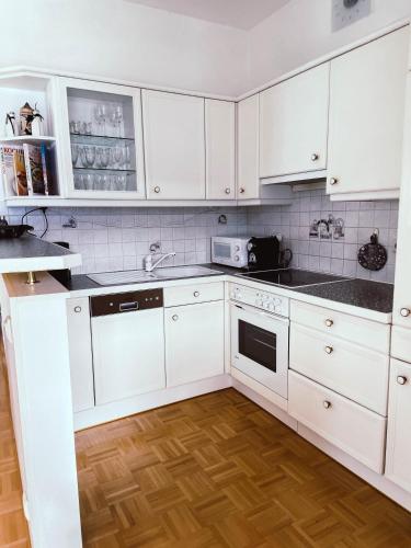 a white kitchen with white cabinets and a wooden floor at Ferienwohnung Karasek mit Seeblick in Sattendorf