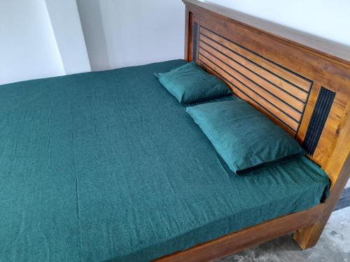 uma cama com uma cabeceira em madeira e lençóis e almofadas verdes em Aruliya care Resort and Spa em Galle