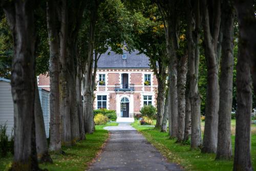 an avenue of trees in front of a brick house at Domaine De Sery in Bouttencourt