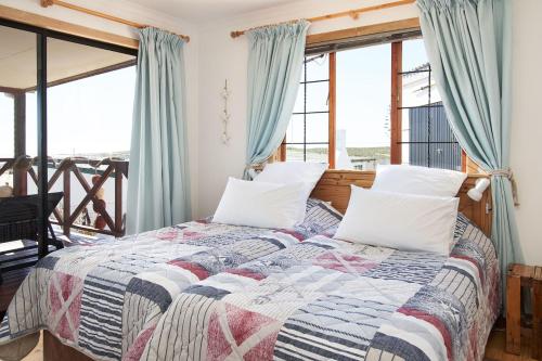 Schlafzimmer mit einem Bett mit blauen Vorhängen in der Unterkunft Dogstone Cottage in Hondeklipbaai