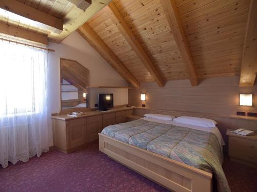 1 dormitorio con 1 cama y TV en Rifugio Capanna Passo Valles, en Falcade