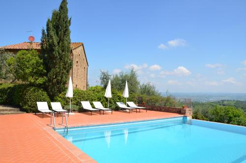 a swimming pool with chairs and umbrellas next to a building at Agriturismo Rigone in Chianti in Montaione