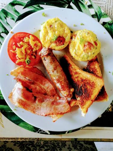 a plate of breakfast food with eggs bacon and tomatoes at The Place Guesthouse Parys in Parys