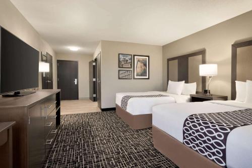 a hotel room with two beds and a flat screen tv at La Quinta Inn & Suites by Wyndham St Louis Route 66 in Saint Louis