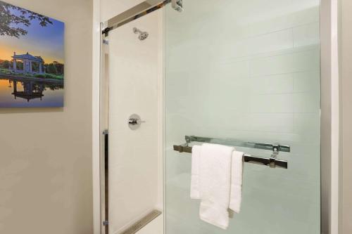a bathroom with a shower with a white towel at La Quinta Inn & Suites by Wyndham St Louis Route 66 in Saint Louis