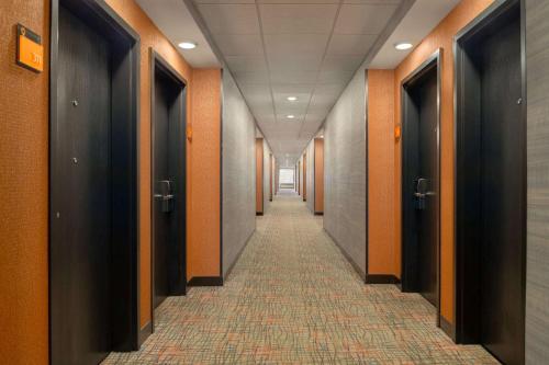 a corridor of a hallway with orange walls and doors at La Quinta Inn & Suites by Wyndham St Louis Route 66 in Saint Louis