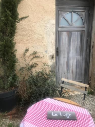 a door to a house with a pink table and a bench at Matin de Saône in Fontaines-Saint-Martin