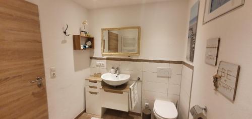 bagno con lavandino, servizi igienici e specchio di Ferienwohnung 1 Rinser mittig in Vogtareuth a Vogtareuth