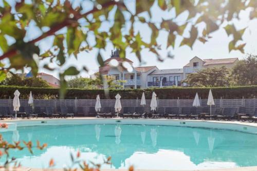 una piscina con sillas y sombrillas blancas en Grand appartement 4 étoiles vue mer et 2 terrasses en Talmont