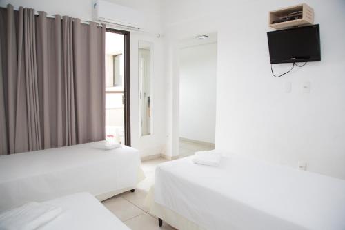 two beds in a room with a tv on the wall at Plaza Inn Trevo Sorocaba in Sorocaba