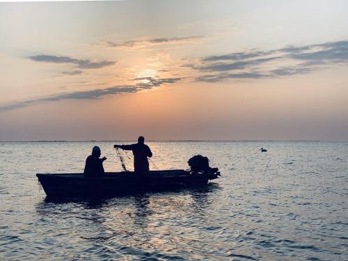 two men on a boat in the water at sunset at Musura Bay Apartments in Sulina