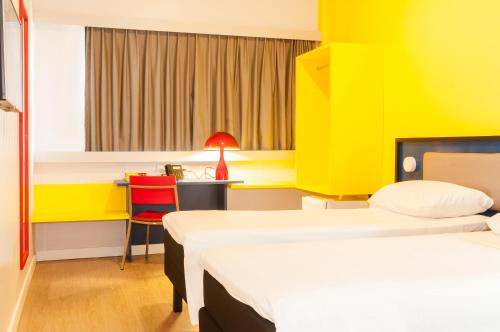 a room with two beds and a desk with a chair at ibis Styles Sao Mateus in São Mateus
