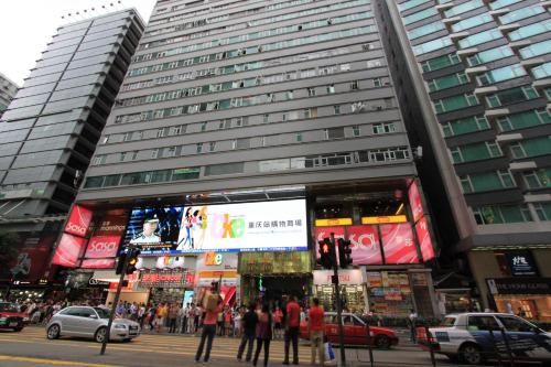 un grupo de personas de pie en frente de un edificio alto en Pay-Less Guesthouse (7/F A9) en Hong Kong