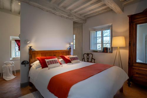a bedroom with a large bed with red pillows at Castello di Volpaia in Radda in Chianti
