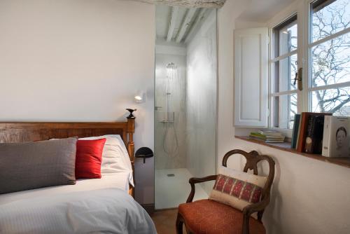 a bedroom with a bed and a chair and windows at Castello di Volpaia in Radda in Chianti