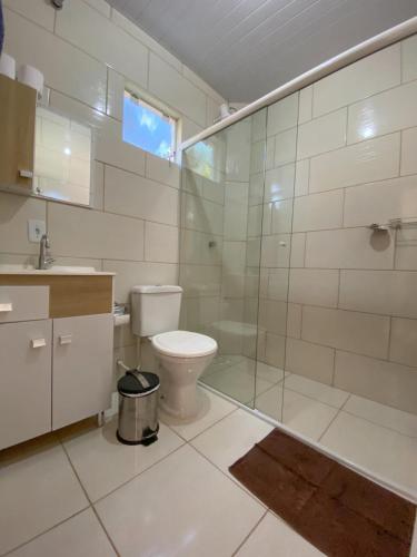 a bathroom with a toilet and a glass shower at Recanto Marina in Guarda do Embaú