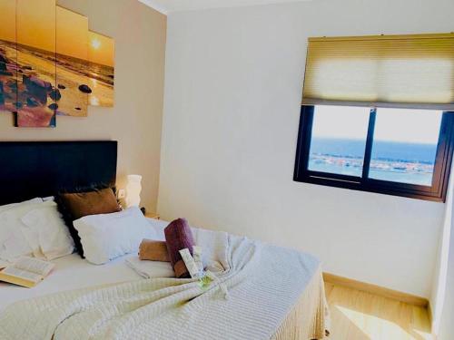 a bedroom with a white bed with a window at Amazing views to Los Cristianos Bay in Achacay in Los Cristianos