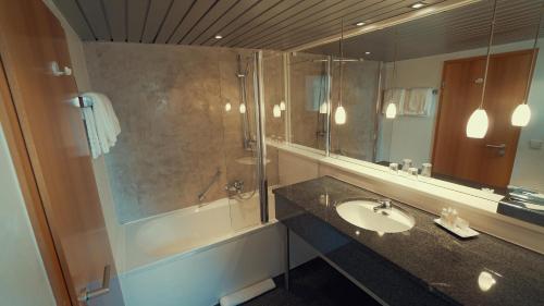a bathroom with a sink and a shower and a mirror at Hotel Adler Asperg in Asperg