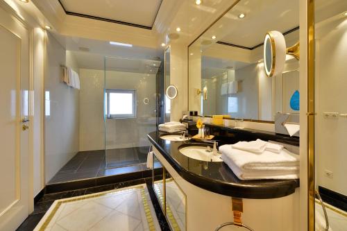 ein Bad mit einem Waschbecken und einem Spiegel in der Unterkunft The Monarch Hotel in Bad Gögging