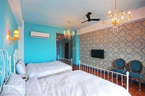 a bedroom with two beds and a blue wall at 綠島寧靜海潛水-城堡館 Twinkleocean diving hostel in Green Island