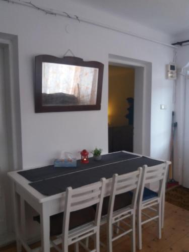 a dining room table with chairs and a tv on the wall at Apartament La poteca ursului in Buşteni