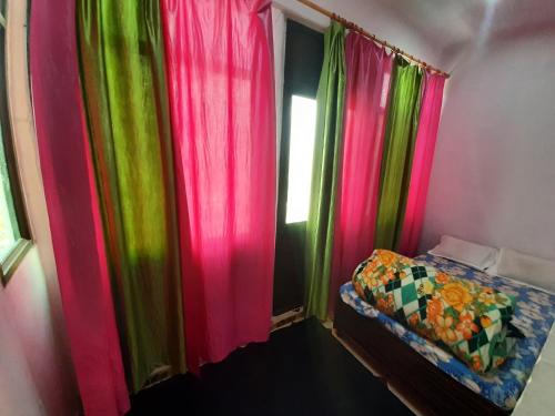 a bedroom with pink and green curtains and a bed at Hotel Himalayan Dews Ukhimath in Ukhimath