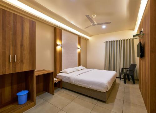 a bedroom with a bed and a desk and a chair at Hotel Kiyara in Kolhapur