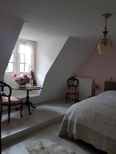Un dormitorio con una cama y una mesa con flores. en TERP WONING bij Schiermonnikoog "Op de Terp" Noordoost Friesland, en Ee