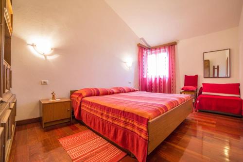 sypialnia z dużym łóżkiem i czerwonym krzesłem w obiekcie Apartment Andrea 329 w mieście Vodnjan