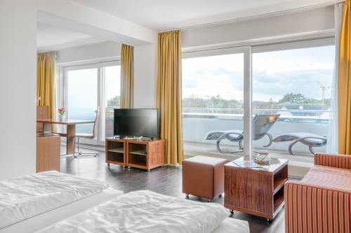 a hotel room with a bed and a television and a balcony at Ferienwohnung Yachtclub in Timmendorfer Strand