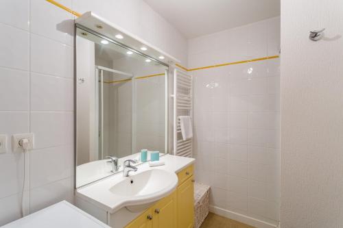 La salle de bains blanche est pourvue d'un lavabo et d'un miroir. dans l'établissement L'Astrolabe, à Dinard
