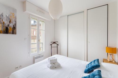 1 dormitorio blanco con 1 cama grande con almohadas azules en L'Astrolabe, en Dinard