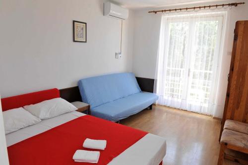 Apartments Popovac 736 في غراداك: غرفة نوم بسرير احمر وزرق وكرسي