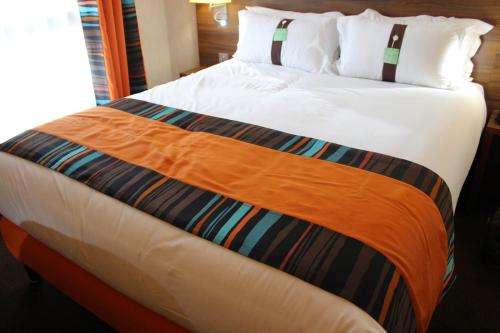 duże łóżko z pomarańczowym kocem w obiekcie Holiday Inn Paris Montmartre, an IHG Hotel w Paryżu