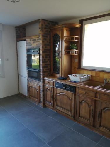 une cuisine avec des armoires en bois et un réfrigérateur blanc dans l'établissement LE BELLEVUE 47 gîte touristique 3 étoiles, à Bricqueville-sur-Mer