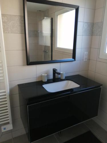 une salle de bain avec un lavabo noir et un miroir dans l'établissement LE BELLEVUE 47 gîte touristique 3 étoiles, à Bricqueville-sur-Mer