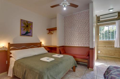 a bedroom with a bed and a chair and a window at Residencial Jade in Florianópolis