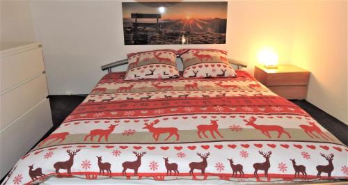 a bed with a red bedspread with deer on it at Anniviers : studio avec mezzanine in Vissoie